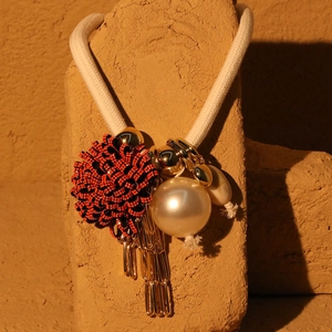 Detailed shot of bohemian chunky rope necklace with pearl and gold metal fringe charms
