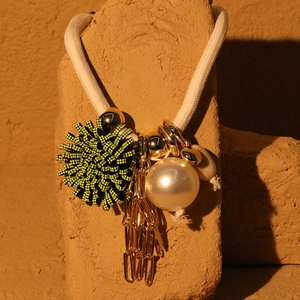Detail of flower necklace with woven ball, faux pearl and golden fringe tassels