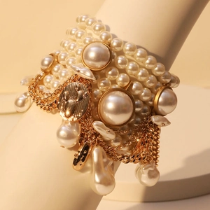 Multilayer faux pearl bracelet with gold tassel charms on a white display stand