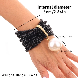 Close-up of multi-layer beaded bracelet with a large white pearl charm on female wrist