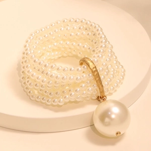 Detailed shot of multi-layer faux pearl bracelet featuring a large round pearl pendant
