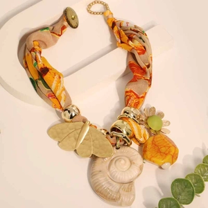 Detail of bohemian butterfly and conch shell pendants on floral fabric necklace