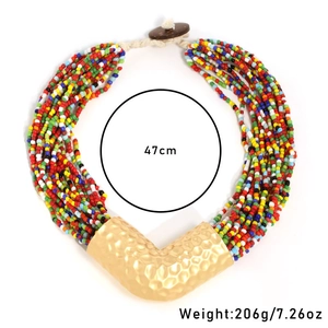 Dettaglio collana a strati con perline colorate ed elemento in metallo dorato opaco a V