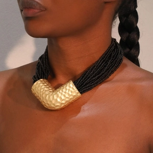Collana multifilo di perle nere con un pendente a V in metallo dorato martellato