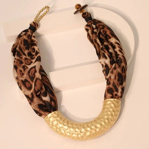 Detail of U-shaped gold hammered metal with leopard print fabric on a minimalist stone