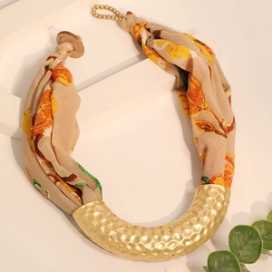 Close-up of golden hammered U-shape metal tube with floral silk scarf bohemian necklace