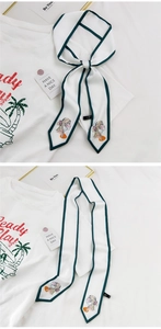 Détail d'un long foulard en soie avec bordure verte et illustration artistique de sac