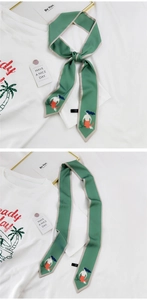 Détail d'un foulard Twilly en soie vert forêt avec imprimé sirène et style noué élégant