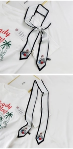 Détail d'un foulard étroit en soie avec bordure noire et dessin de mode