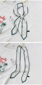 Détail d'un foulard long en soie à motif géométrique crème et vert sur un t-shirt