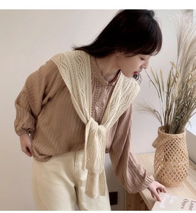 Detail eines zarten Strickschals mit Lochmuster und einem Vintage-Streifenhemd
