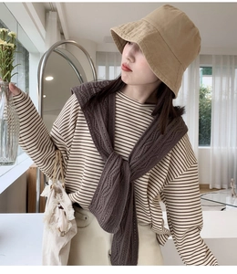 Detail eines dunkelbraunen Strickschals mit Zopfmuster über gestreiftem Hemd