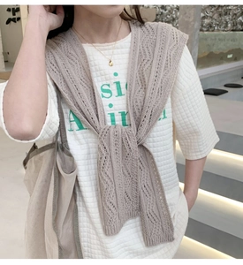 Detail eines helltaupefarbenen Strickschals mit Wellenmuster und Rippbündchen