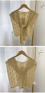 Detail eines beigen Strickschals mit Wellenstruktur und Bindeband am Holz-Kleiderbügel