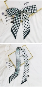 Détail d'un foulard en soie à motif pied-de-poule noué en boucle sur fond texturé