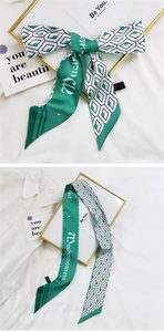 Détail d'un foulard en soie à motif géométrique vert et blanc avec lettrage de marque