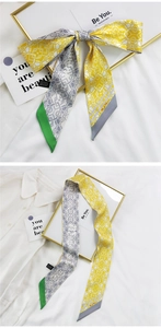 Détail d'un foulard en soie jaune et gris noué en nœud sur une chemise blanche