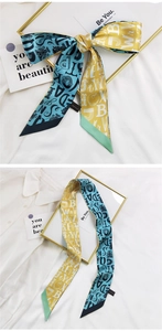 Détail d'un foulard en soie jaune et bleu avec imprimé lettres noué en nœud