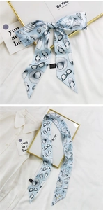 Détails d'un foulard en soie bleu clair avec imprimés d'été et nœud élégant