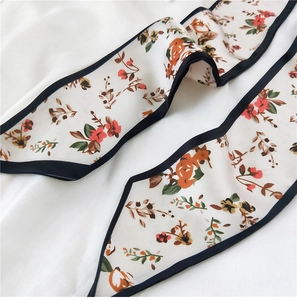 Détail d'un foulard en soie avec imprimés floraux vintage et bords ourlés noirs