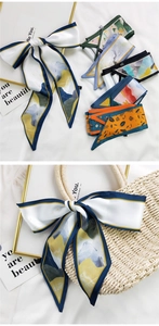 Détail d'un foulard en soie imprimé noué sur l'anse d'un sac en paille style vacances