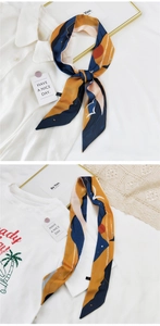 Détail d'un foulard mince en soie avec motif de paysage abstrait bleu et orange sur blanc
