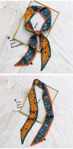 Détail d'un ruban en soie floral bleu et orange avec slogan et motifs de feuilles