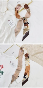 Détail d'un foulard étroit en soie à motif pomme sur une chemise et un t-shirt blancs