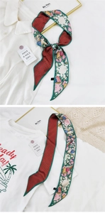 Détail d'un foulard étroit en soie avec imprimé floral vert émeraude et étiquette