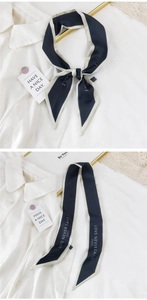Détail d'un foulard étroit bleu marine avec texte blanc LOVE NEVER FAILS PARIS imprimé