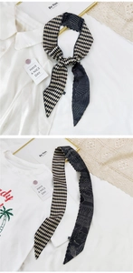 Détail d'un foulard étroit en soie noir et blanc avec des motifs de lignes architecturales