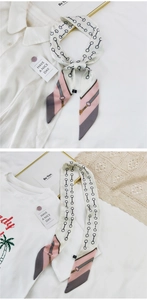 Détail d'un foulard en soie étroit à motif mors noué en nœud sur une chemise blanche