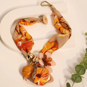 Détail du collier floral bohème en tissu avec pétales orange et billes en métal doré