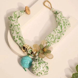 Détail du collier bohème en tissu avec fleur en résine et ruban imprimé cœurs verts