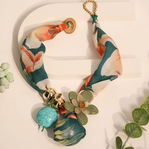 Détail de collier floral bohème en tissu avec perles dorées sur support