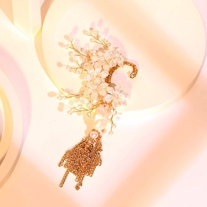 Floral bridal ear cuff with baroque pearls and golden tassels on a minimalist stand