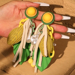 Boucles d'oreilles pendantes feuille avec perles jaunes et chaînes sur fond de pierre