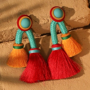 Macro detail of Bohemian tassel earrings with turquoise beads and red fringe on stone