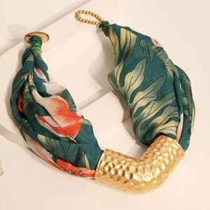 Detail of V-shaped bohemian pendant with floral fabric and hammered gold metal texture