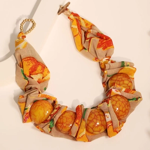 Détail d'un collier boho ethnique avec perles enveloppées de tissu et fermoir bouton bois