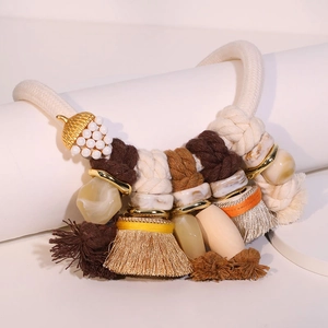 Bohemian fringe necklace with yellow tassels and white pearl acorn on light background