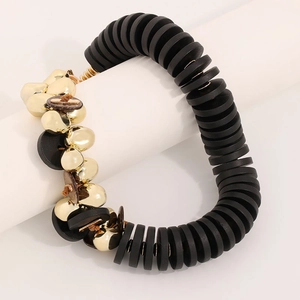 Collier artisanal en noix de coco avec disques noirs et perles dorées sur support blanc