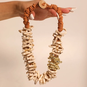 Handmade chunky necklace featuring cream resin rings, gold metal, and orange woven rope