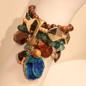 Detail of bohemian layered beaded bracelet with green druzy pendant and wooden accents