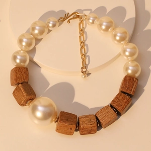 Handmade necklace with large faux pearls and wooden beads on a round display stand