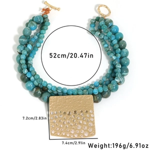 Detail showing bohemian layered turquoise beads and large hammered gold pendant on necklace