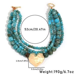 Detail of layered turquoise beaded necklace with large gold heart pendant and T-bar clasp
