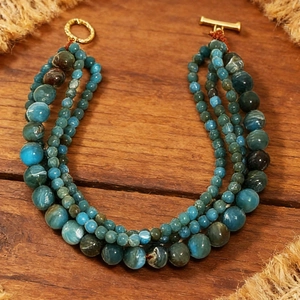 Detailed view of triple-layered teal beaded necklace with vintage gold OT toggle clasp