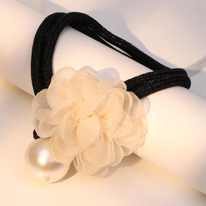 Macro view of vintage organza flower and large pearl detail on a black elastic hair tie