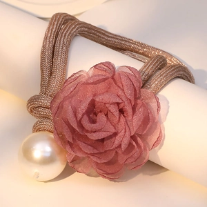 Detail of elegant pink fabric flower necklace with gold braided rope and large white pearl
